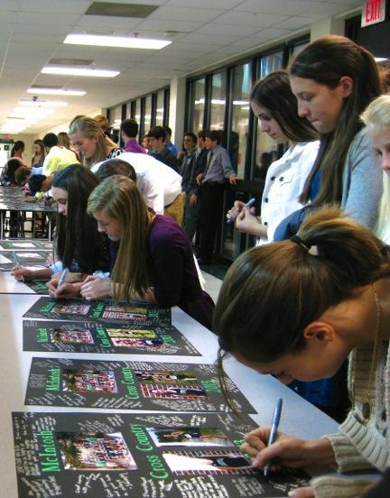 Cross country teammates line up to sign senior picture frame gifts