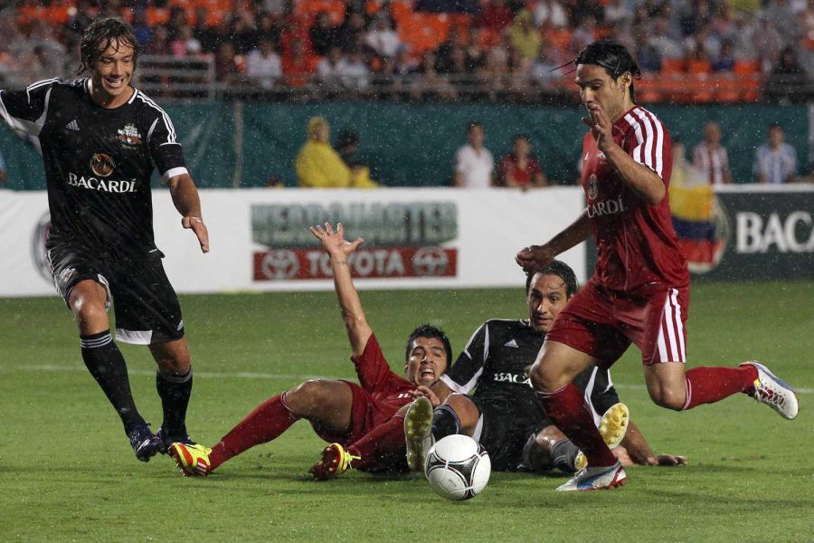 Luis Suarez, who was transferred to Barcelona for $122 million, falls on the ground as Radamel Falcao, who was loaned to Manchester United for $9.79 million, shoots.