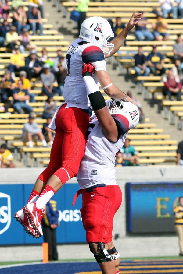 An Arizona teammate lifts up his fellow team member as they celebrate the completion of the hail mary pass that kept their season unblemished