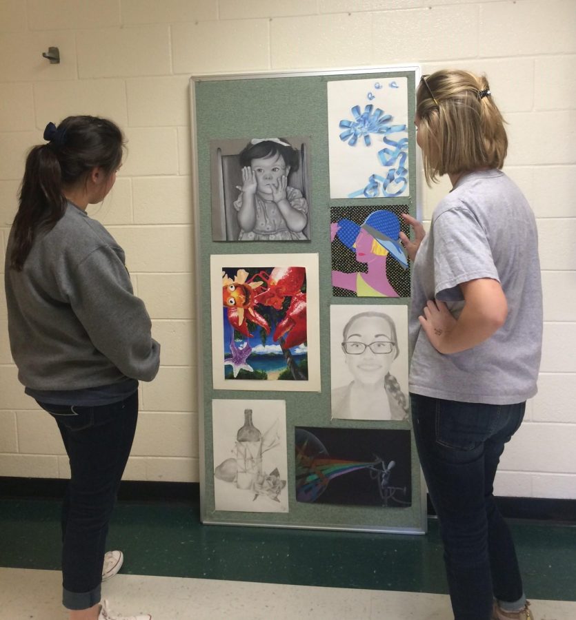 Two students admire some of the artwork that will be displayed at the art show.