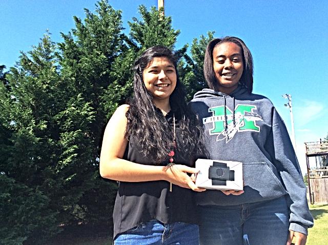 Freshmen Lisbeth Pena and Amber Galloway display the camera they created out of a small cardboard box. A few minutes before this photo was taken, these students took a photo of their own using their pinhole camera.