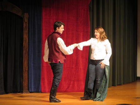 Actors portraying Romeo and Juliet hold hands and exchange glances.