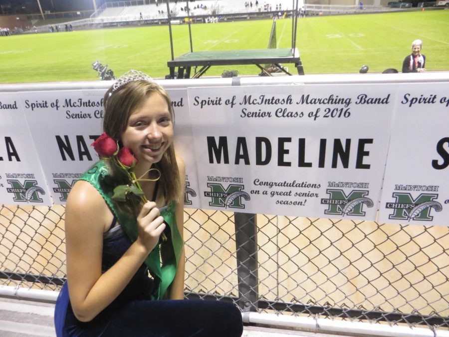Senor color guard member Madeline Lyons celebrates senior night with roses and a custom sign.