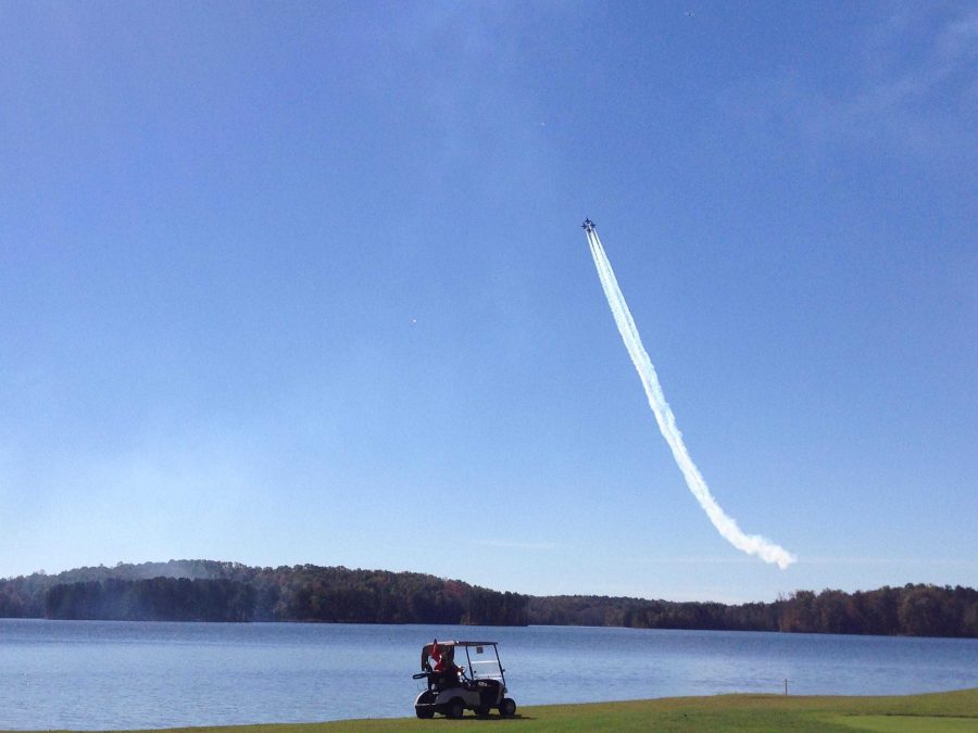 A Blue Angels F/A-18 flies over a golf cart near Lake Peachtree Friday.