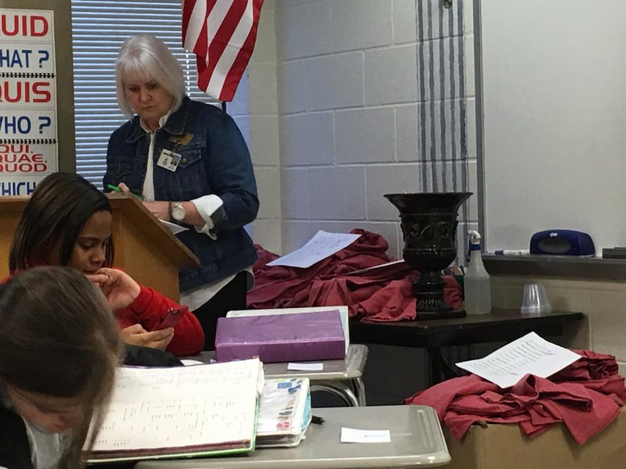 Ms. Bryant checks a list to verify which club members will receive their shirts.