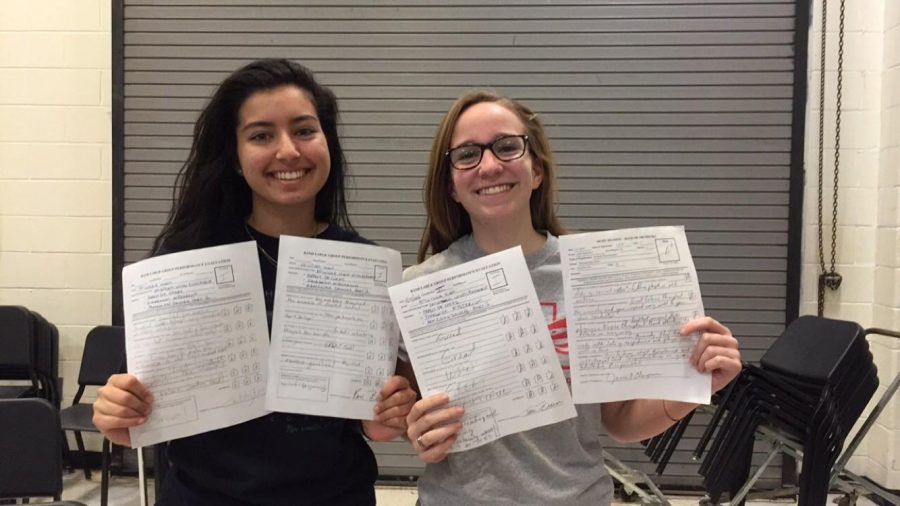Junior Alexandra Dumas and senior Rachel Anders proudly show off judges sheets from the performance.