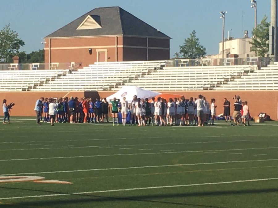 The team talks to Head Coach Marcia Clark and Assistant Coach John Briglevich.
