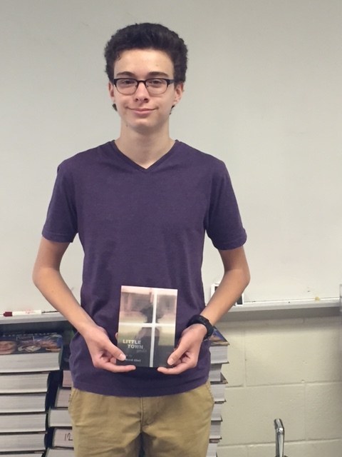 Sophomore Sam Ellis holds Mr. Abels newest book of poetry as his prize for winning first place in the debate tournament.  