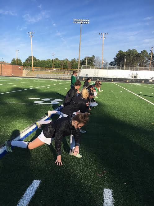 The varsity girls soccer team warms up before their game against Morrow High School. This game is the first to take place on the new turf field.