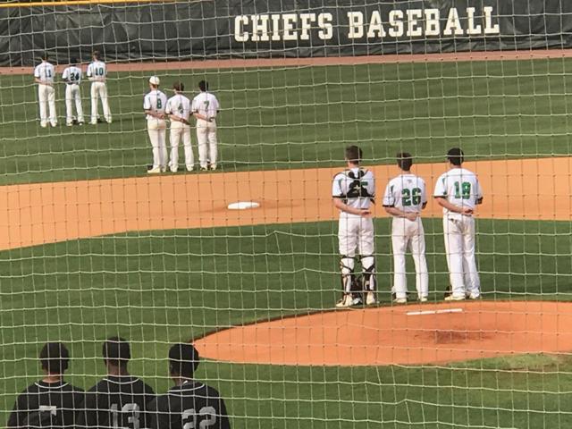The varsity baseball team stands during the Pledge of Allegiance at their game against Riverdale High School.