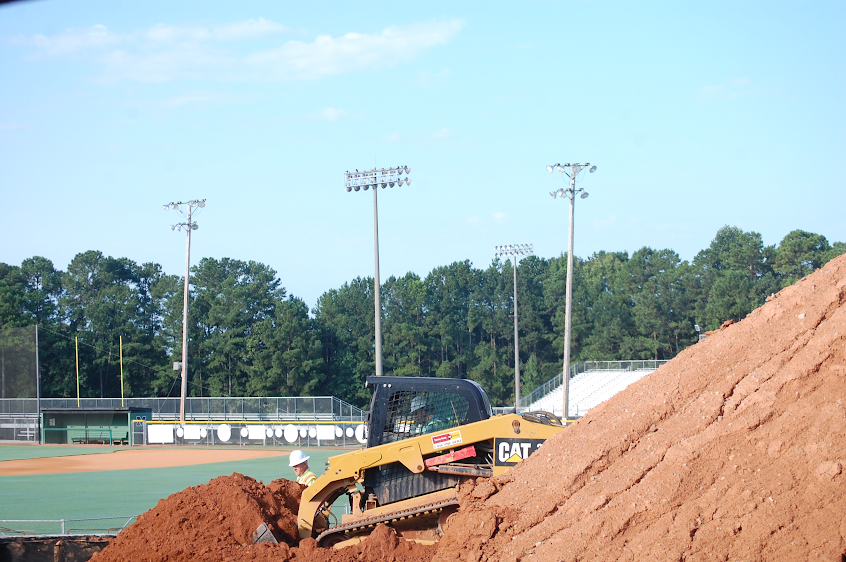 Bulldozer takes dirt from mound and moves it to the concrete foundation.