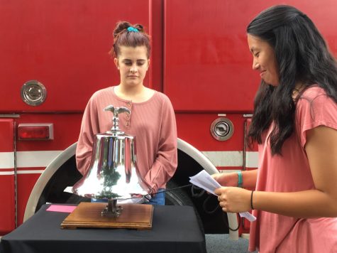 Sophomores Nadia Post and Lila Slay stand by the bell. Nadia Post reads a name off of a card and rings the bell three times. Lila Slay stops the bell after the third ring to symbolize the death of a person.
