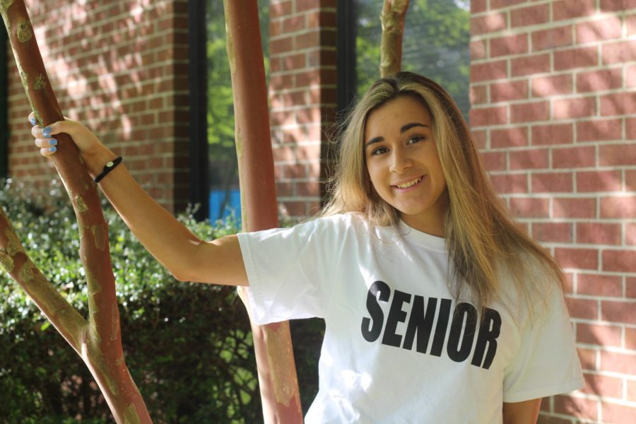 Senior Cailey Hardman poses in the courtyard while wearing her senior shirt.