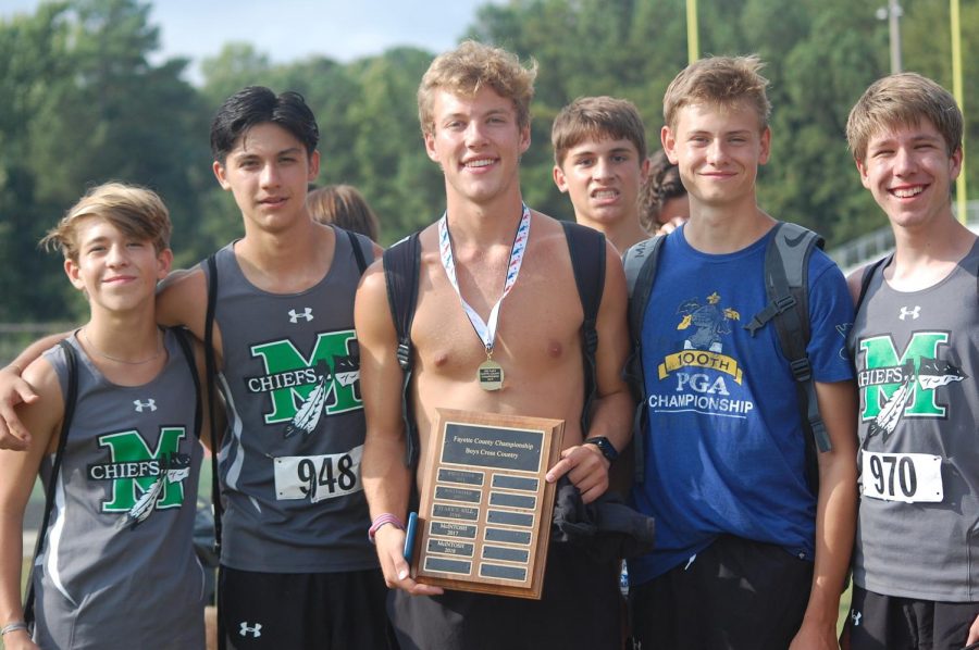 McIntosh XC boys runners pose with their Fayette County Championship Boys Cross Country plaque.