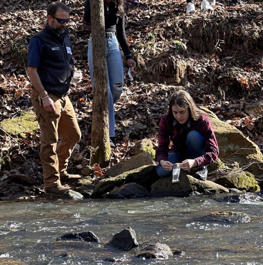 Member of Adopt-a-Stream LilyRose Costello (10) collects water samples with Fayette County Instructor Ben Martin standing on the left. Courtesy of Mary Beth Grabhorn
