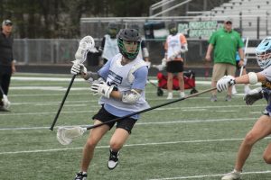 Boys varsity lacrosse player dodges his teammates stick while in practice.