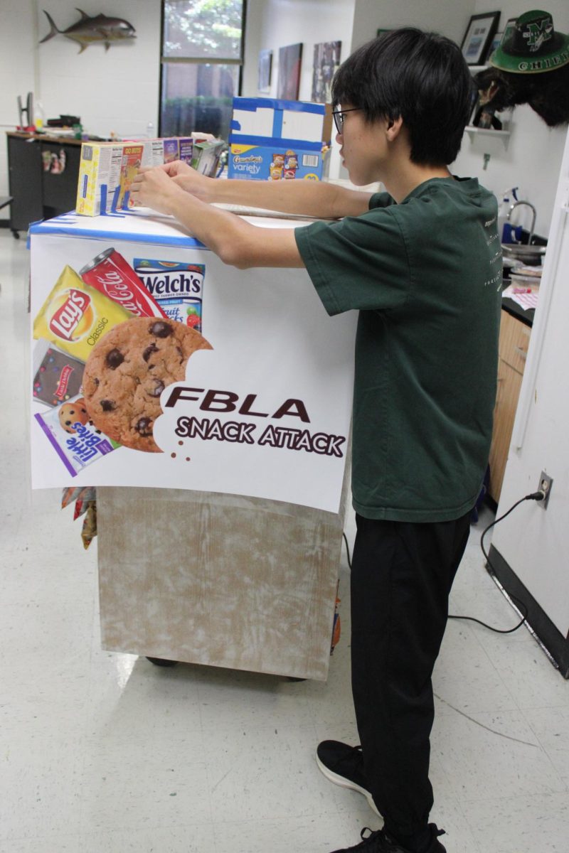 Helping to set up the snack cart Brian Lin (10) takes inventory, sets up the display and restocks snacks. Photo by Camilia O'Connell. 