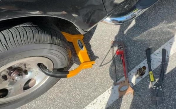 An image of a student's car with a boot on the back right tire and tools to attempt to remove it.