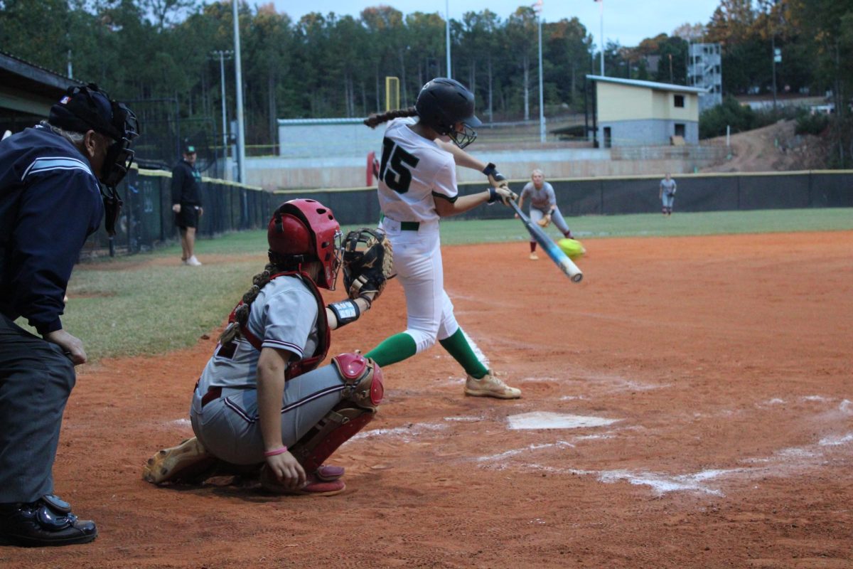 Junior Izzy Ambrose preparing to hit the ball as it crosses over home plate.