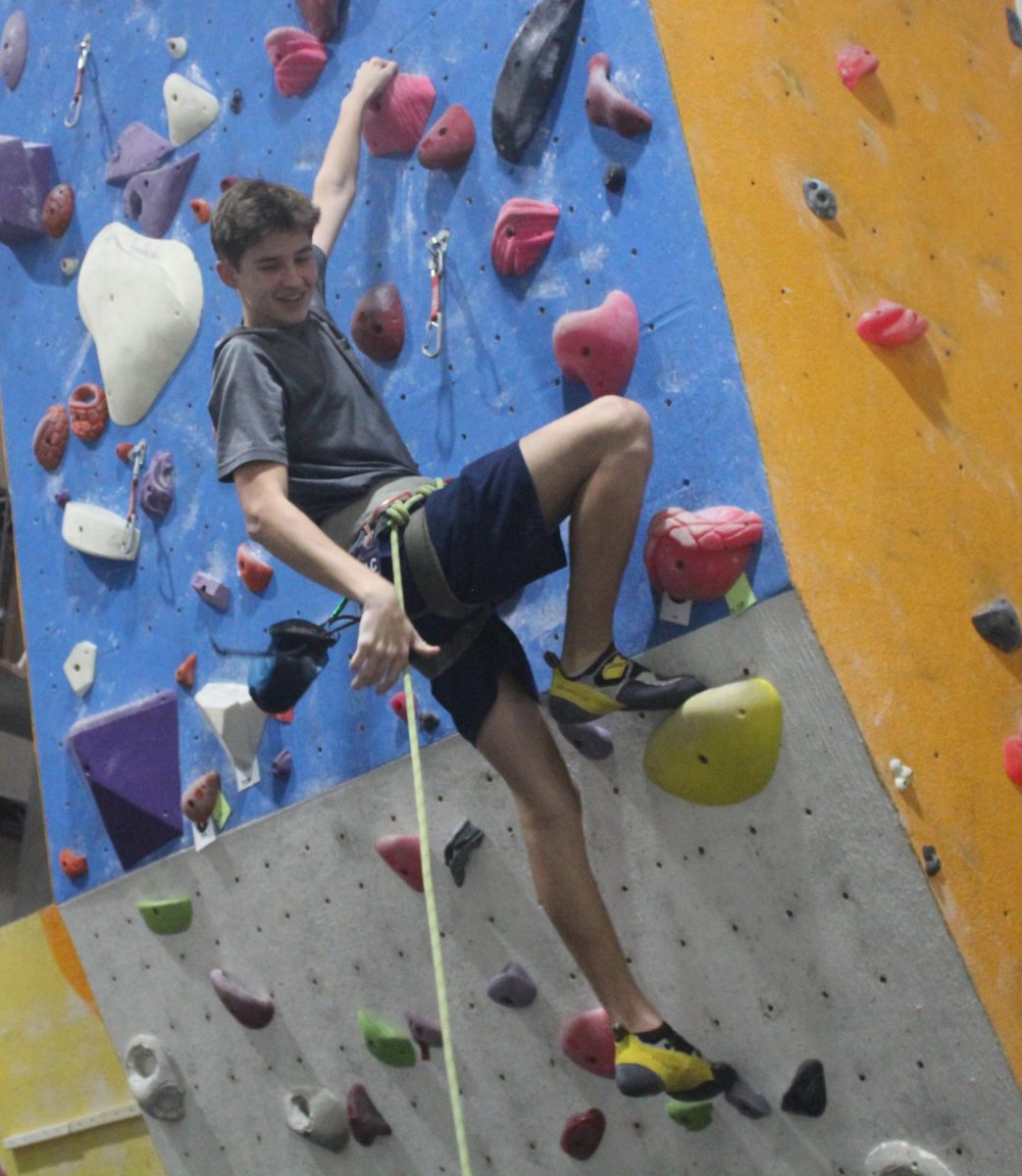Freshman Max Haber climbing a rock wall at Escalade ptc.