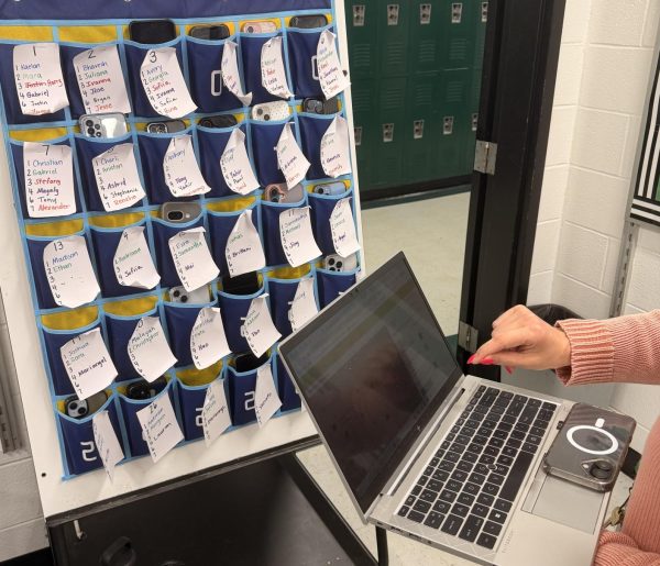 Teacher taking student attendance in classroom using a phone caddy to ensure compliance 