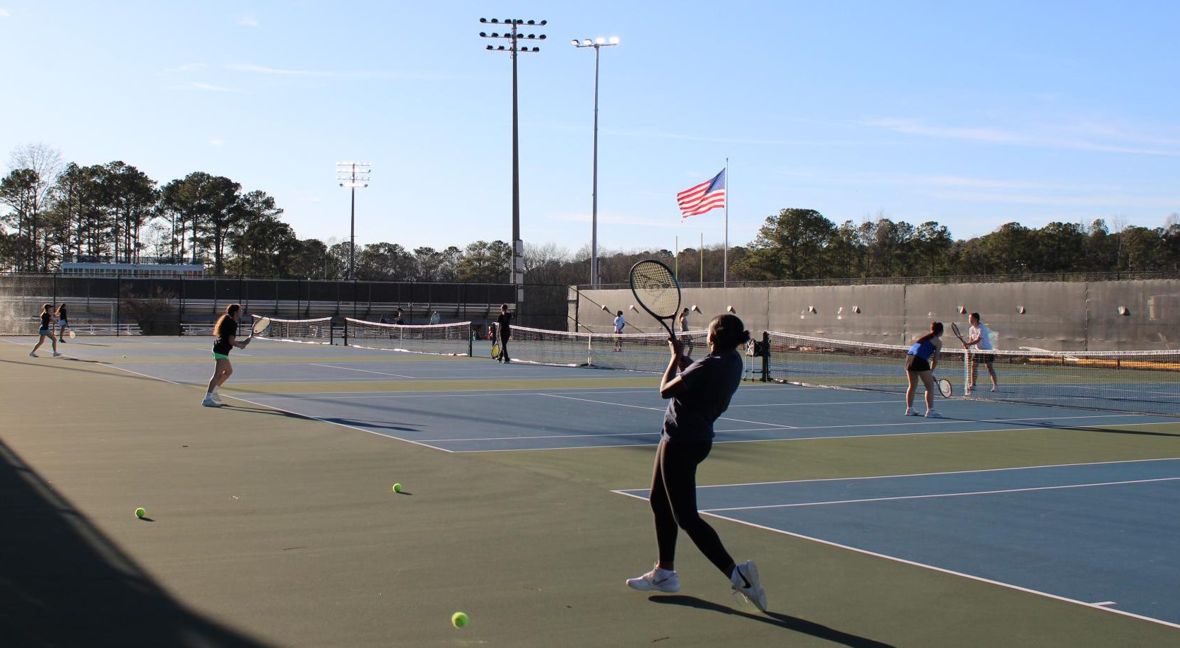 Girls varsity and junior varsity tennis practicing on their courts