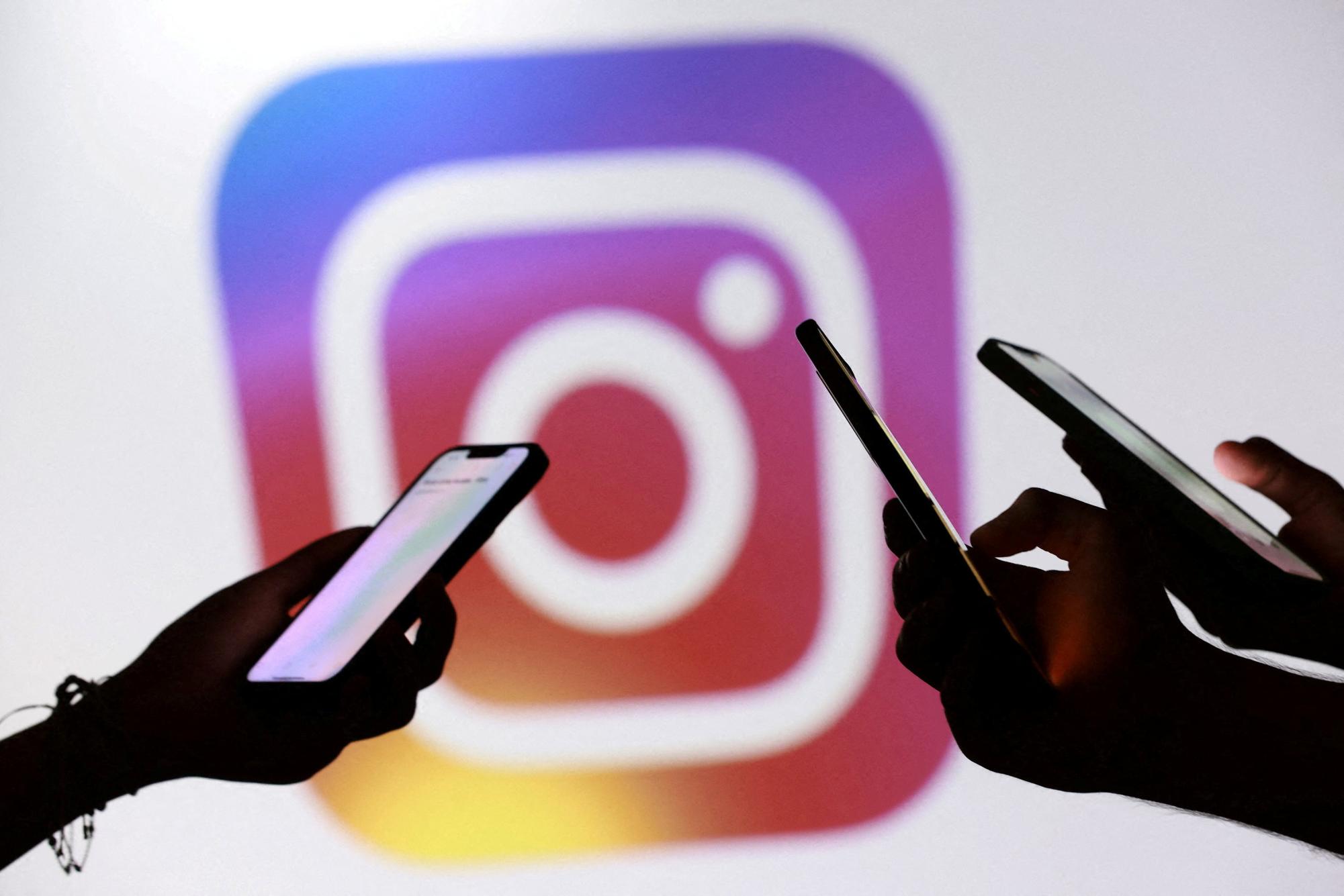 People posed for a photo while holding smartphones in front of the Instagram logo in this illustration taken September 11, 2025. REUTERS/Dado Ruvic/Illustration